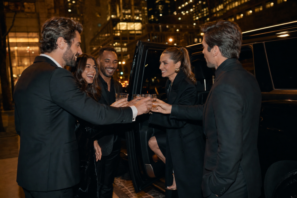 Friends toasting as they board a black luxury SUV at night on a Chicago street — Maven's Choice party limo service
